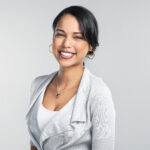 Studio shot of a confident young businesswoman posing against a grey background.